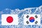 The flag of Japan and South Korea are painted at opposite end of piece of ice in the form of an arctic iceberg against blue sky.