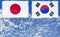The flag of Japan and South Korea are painted at opposite end of piece of ice in the form of an arctic iceberg against blue sky.