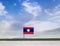 Flag of Laos with vast meadow and blue sky behind it.