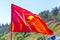 The flag of the Leninist Komsomol flies in the Grushinskaya glade against the blue sky