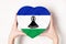 Flag of Lesotho on a heart shaped box in a female hands. White background