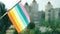 Flag of the LGBTQ set against blue sky and city street. LGBTQIA flag waving. Rainbow stripes on colorful LGBT flag. The holiday