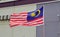 Flag of Malaysia waving in the air with typical building in the background