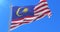 Flag of Malaysia waving at wind with blue sky in slow, loop