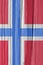 The flag of Norway on a dry wooden surface, cracked with age. Light pale faded paint. Vertical background or wallpaper with