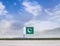 Flag of Pakistan with vast meadow and blue sky behind it.