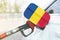 Flag of Romania on the car`s fuel filler flap with gas pump nozzle in the tank