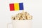 The flag of Romania sticks out of a cup with cubes on which letters are depicted