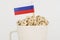 The flag of Russia sticks out of a cup with cubes on which letters are depicted