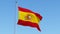 Flag of Spain waving against blue sky.