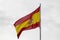 Flag of Spain waving on white sky.