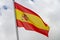 Flag of Spain waving in the wind on flagpole against the sky with clouds on sunny day