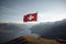 The flag of Switzerland on the background of a mountain landscape. A trip to Switzerland