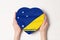 Flag of Tokelau on a heart shaped box in a female hands. White background