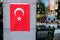 The flag of Turkey is vertically located on the column of the building background vertina
