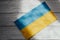 The flag of Ukraine is blue and yellow on the background of wooden figured boards.