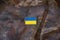 The flag of Ukraine with a stripe on the military uniform of a Ukrainian soldier hangs on a military camouflage mesh