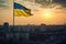 The flag of Ukraine waves proudly in a big city at sunset, symbolizing the country's freedom, unity, and resilience