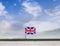 Flag of United Kingdom with vast meadow and blue sky behind it.