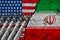 Flag of USA and Iran on textured cracked earth with five ballistic missiles