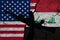 Flag of USA and Iraq on textured cracked earth with a silhouette of a machine gun and hand