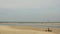 Flag in the wind against the background of people with motorcycles rolling along the light sandy sea coast