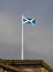 A flagpole with a Scottish flag on display on the roof of a historic building in the city center of Glasgow.