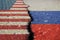 Flags of America and Russia on asphalt are separated by a crack.