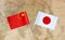 Flags of China and Japan over the world map, political relations concept image