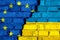 Flags of European union EU and Ukraine on the brick wall with big crack in the middle