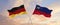 flags of Germany and Liechtenstein waving in the wind on flagpoles against sky with clouds on sunny day. Symbolizing relationship