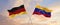 flags of Germany and Venezuela waving in the wind on flagpoles against sky with clouds on sunny day. Symbolizing relationship,