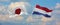flags of Japan and netherlands waving in the wind on flagpoles against sky with clouds on sunny day. Symbolizing relationship,