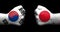 Flags of Japan and South Korea painted on two clenched fists facing each other on black background/.Japanâ€“South Korea relations