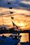 Flags on a sailboat silhouetted by the setting sun.