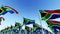 Flags of South Africa on flag poles against blue sky.