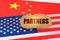 On the flags of the USA and China lies a cardboard sign with the inscription - Partners