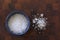 Flake salt lying in a blue bowl and scattered around on a wooden background. Top view image