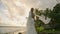 Flamboyant gender fluid black person posing on ocean shore in white chiffon wedding dress. Non-binary bride looks at