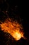 Flame of fire with flying burning red sparks on a black background. Fiery orange glowing particles flying away in night