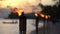 Flame form tiki torch at sunset with silhouette of palm tree in slow motion. Vacation and travel concept.