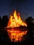 Flames of a huge bonfire at night near lake