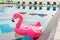 Flamingo float around swimming pool in hotel resort with umbrella and chair in hotel resort