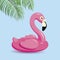 Flamingo inflatable and tropical leaves on blue background