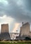 Flash bolt of lightning striking electric power station with cooling tower steam chimneys in storm with dramatic stormy clouds