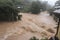 flash flood rushes over bridge and into valley, with houses and roads visible