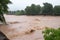 flash flood rushes over riverbank, flooding the surrounding area