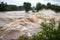 flash flood rushes over riverbank, flooding the surrounding area