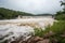 flash flood rushing through broken dam, with water spilling out of the reservoir