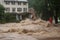 flash flood rushing over riverbank and into neighborhood, with people fleeing the rising water